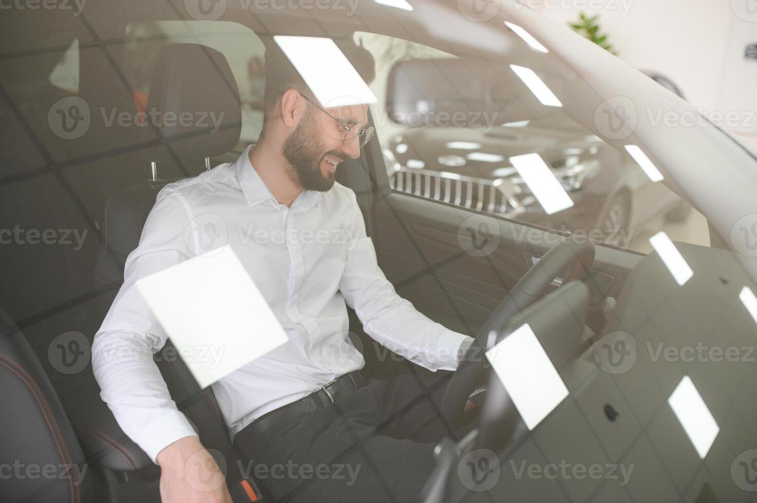 Happy caucasian man in formal wear getting inside luxury modern car for testing interior before purchase. Concept of dealership, selling and purchase photo