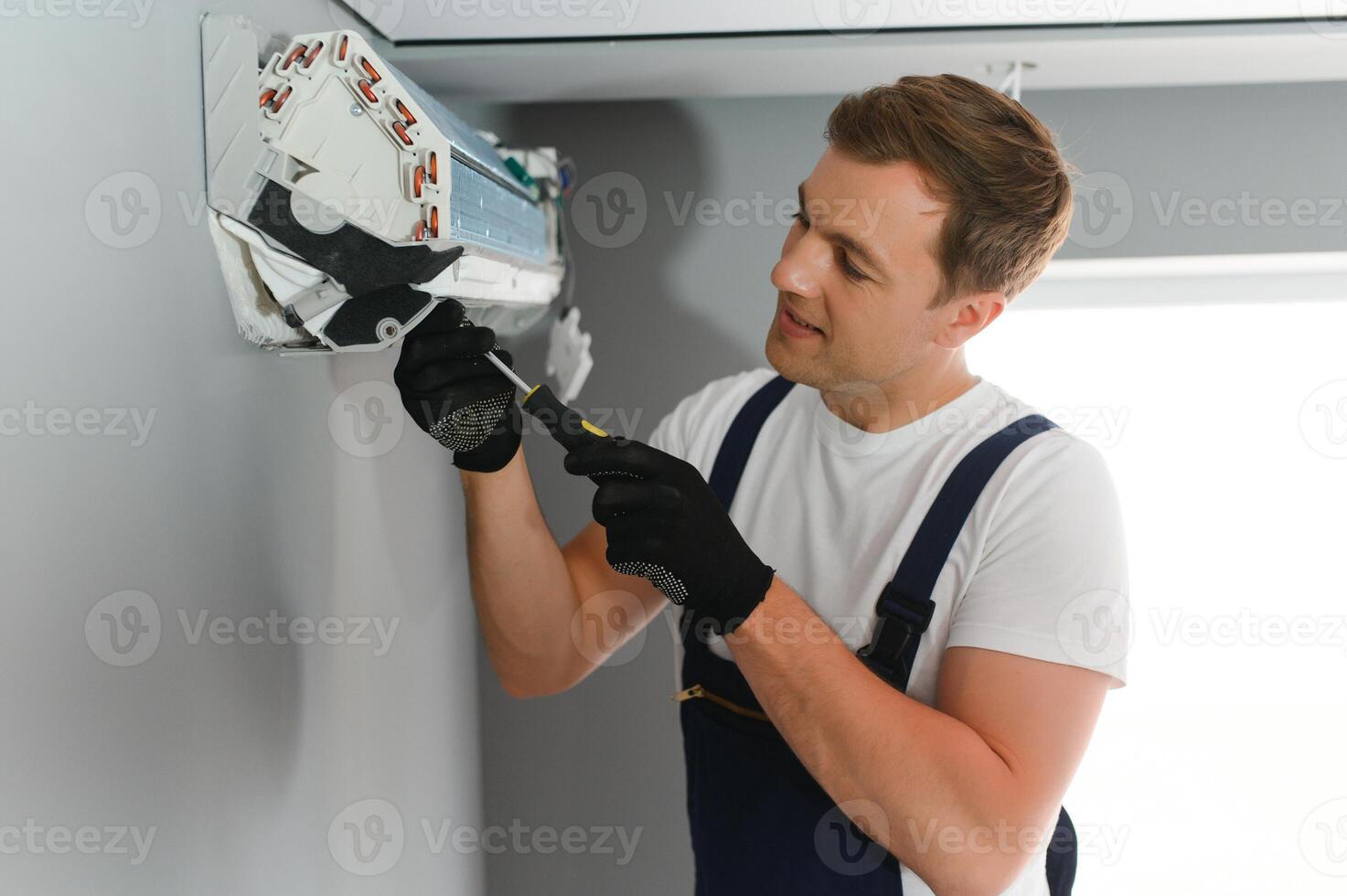 Male technician fixing air conditioner indoors photo