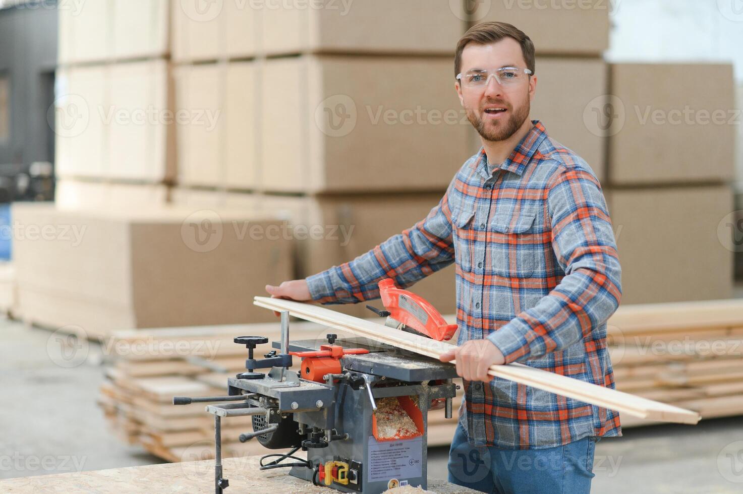 Professional carpenter using sawing machine for cutting wooden board at sawmill. photo