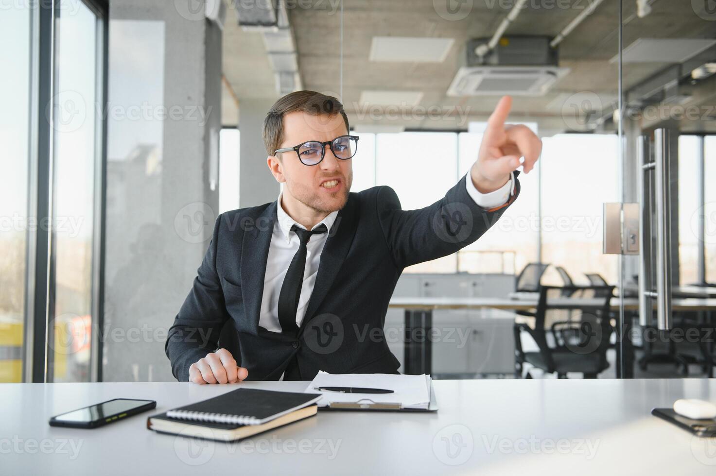 enojado empresario sentado a su escritorio y gritando a su empleados. foto