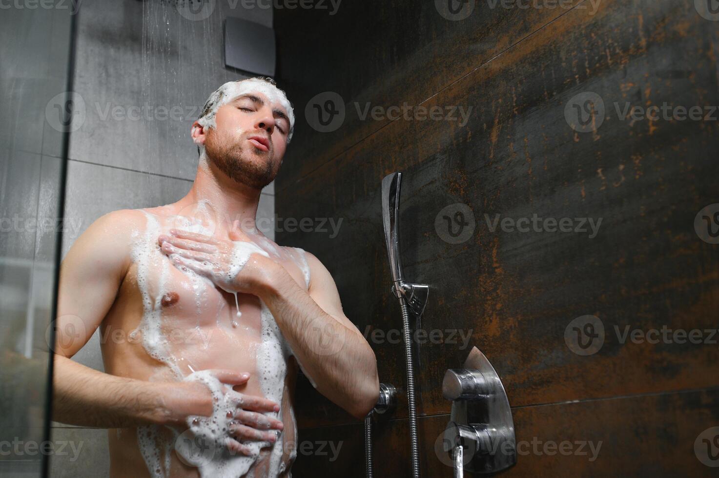 relajante después Estresante día. cintura arriba retrato de desnudo muscular Caballero tomando ducha a hogar. foto
