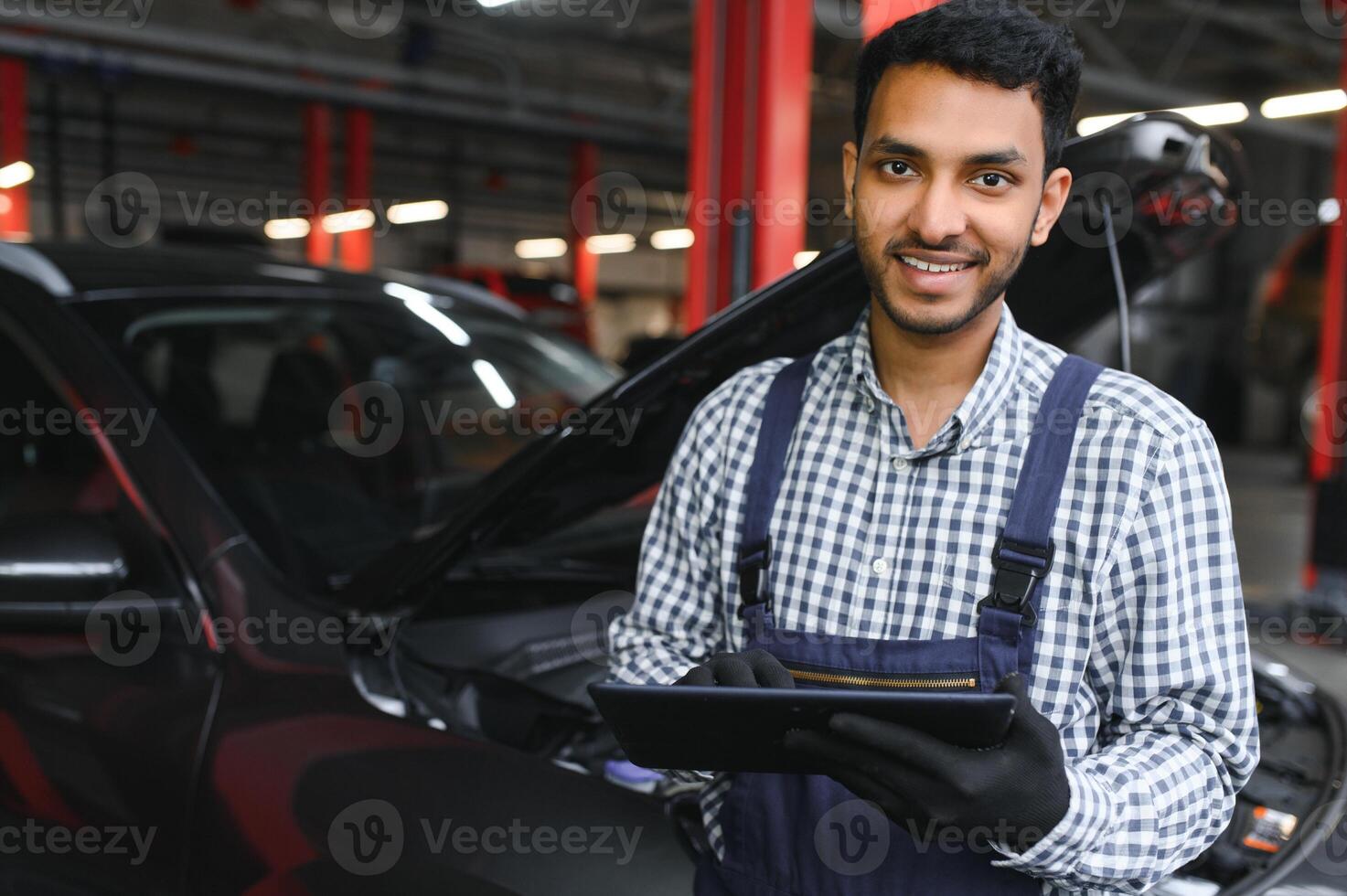 Mechanic man mechanic manager worker using a laptop computer checking car in workshop at auto car repair service center. Engineer young man looking at inspection vehicle details under car hood. photo