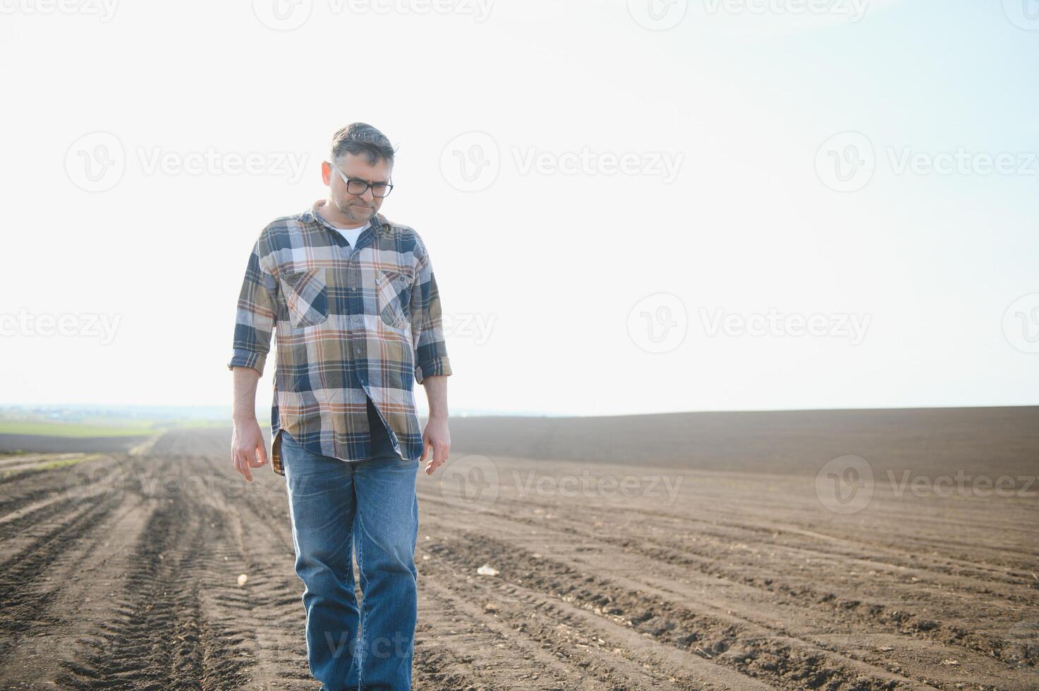 A farmer works in a field sown in spring. An agronomist walks the earth, assessing a plowed field in autumn. Agriculture. Smart farming technologies. photo