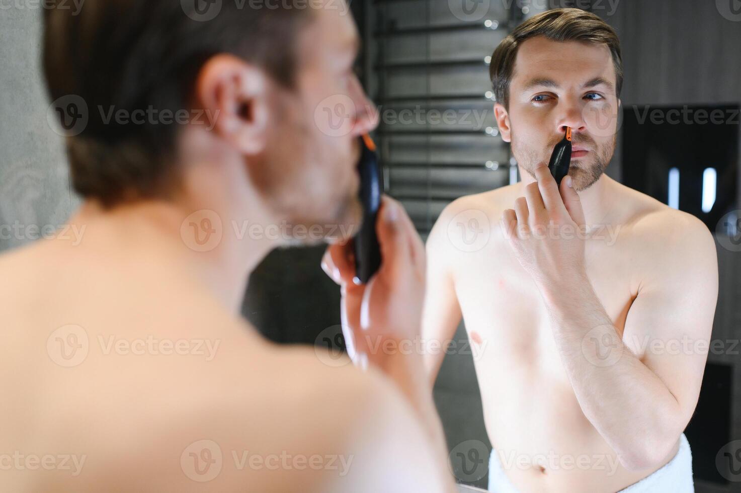 Man using trimmer to remove hair from his nose photo