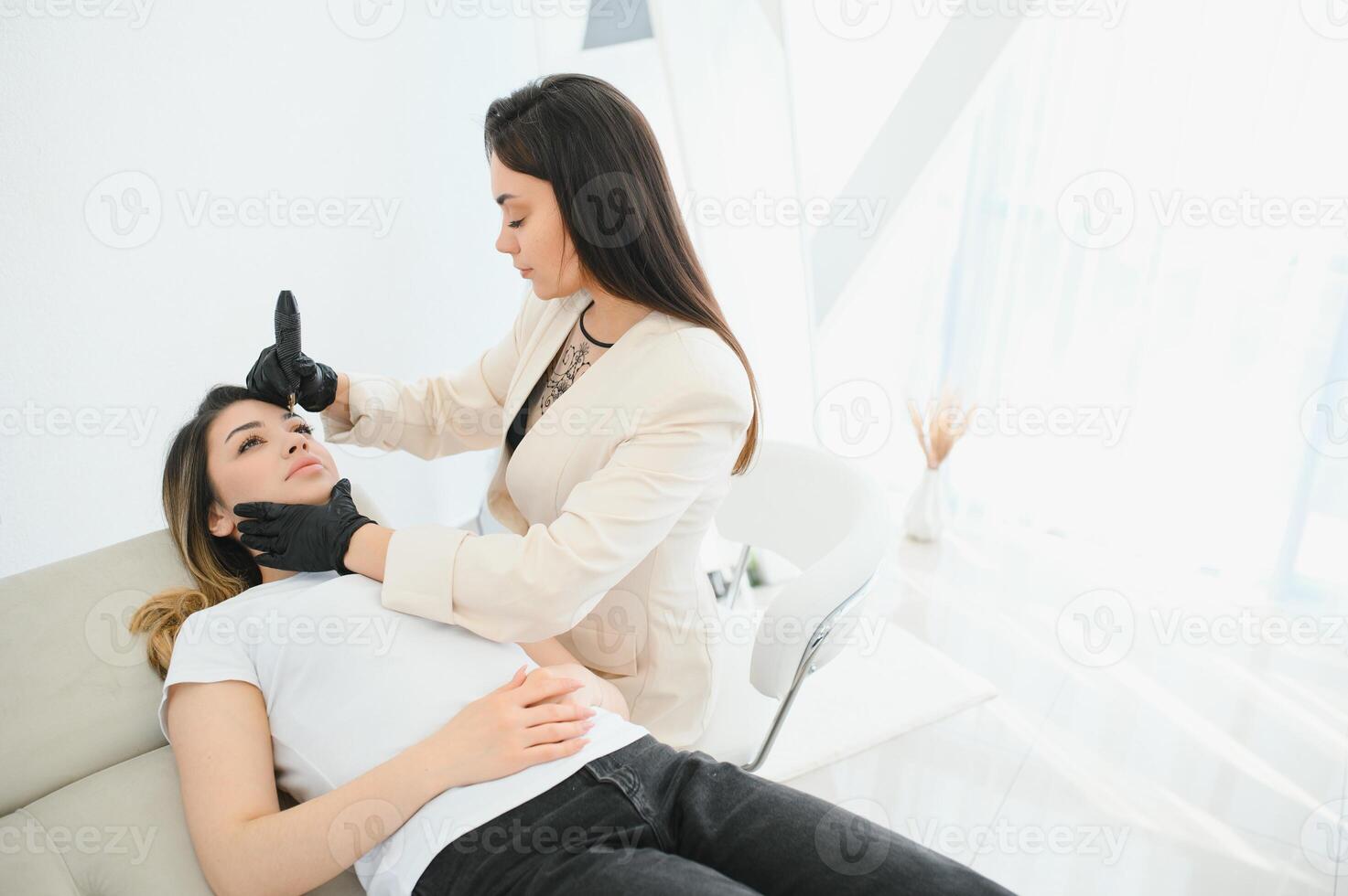 Young woman during procedure of permanent eyebrow makeup photo