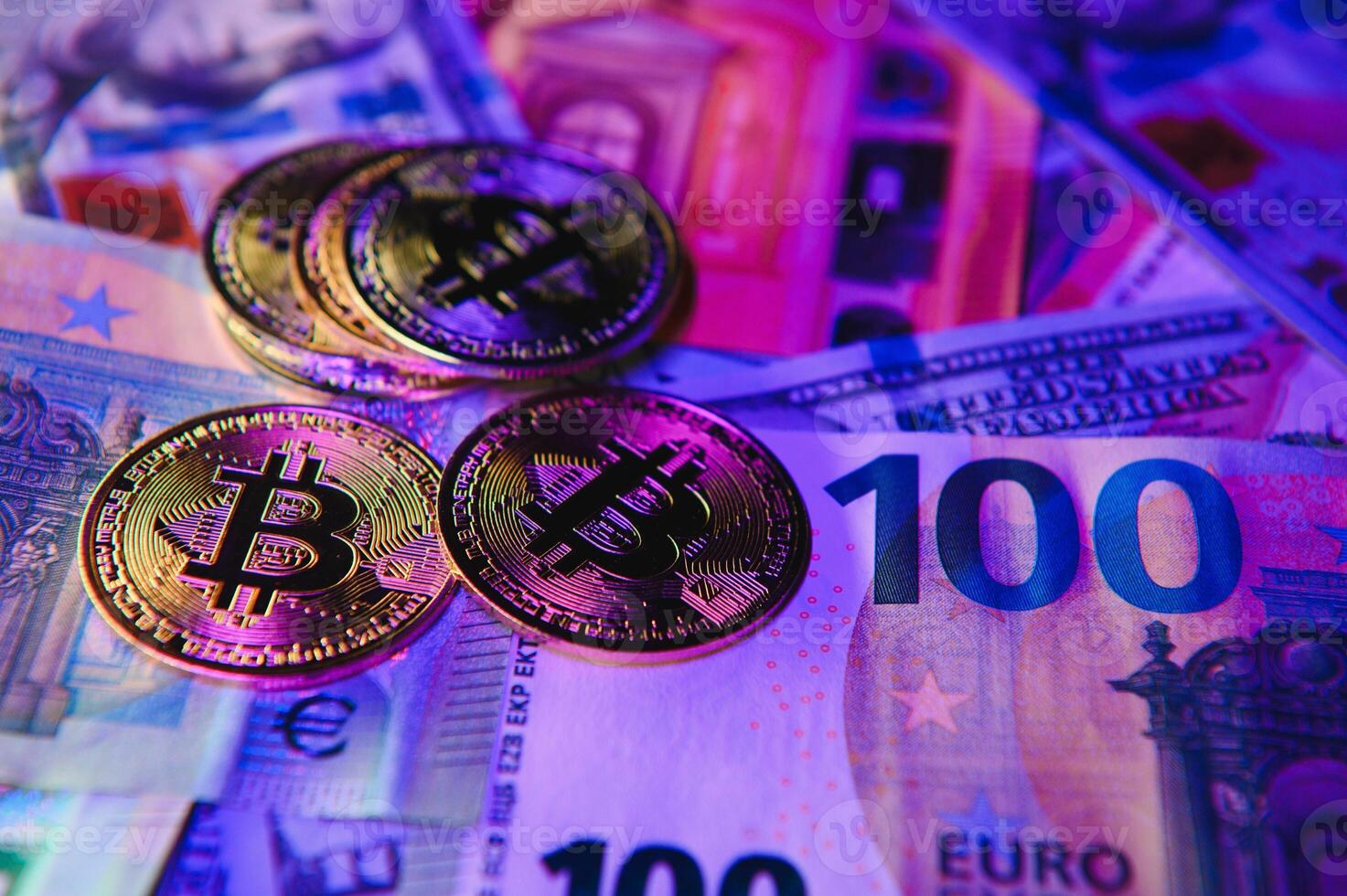 Close up heap of golden bitcoin physical coins on top of Euro, dollar banknotes background, high angle view, selective focus photo