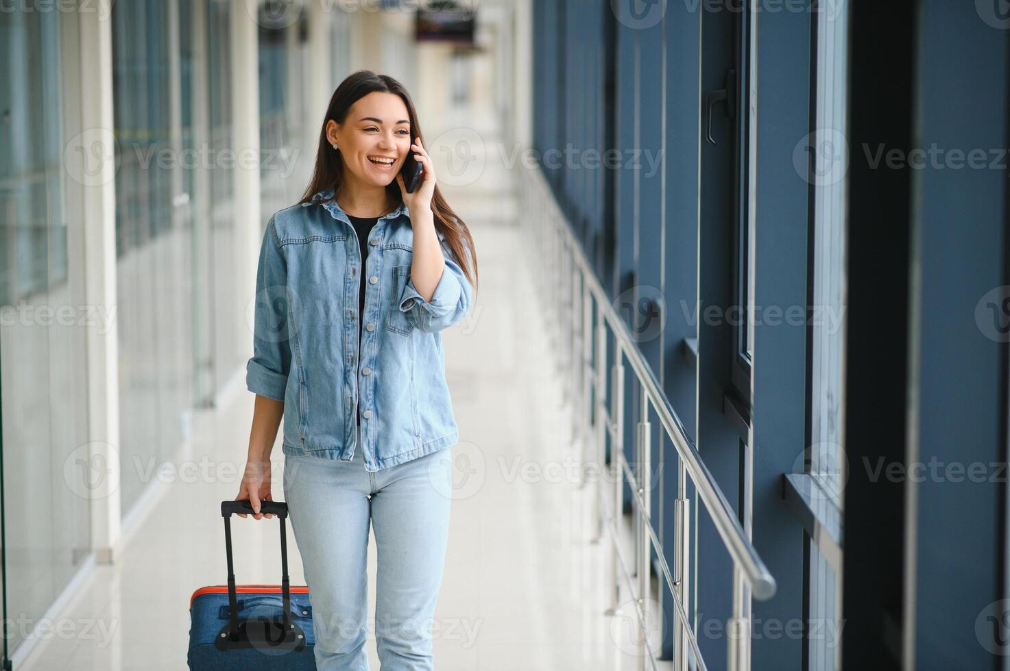 Young woman pulling suitcase in airport terminal. Copy space photo