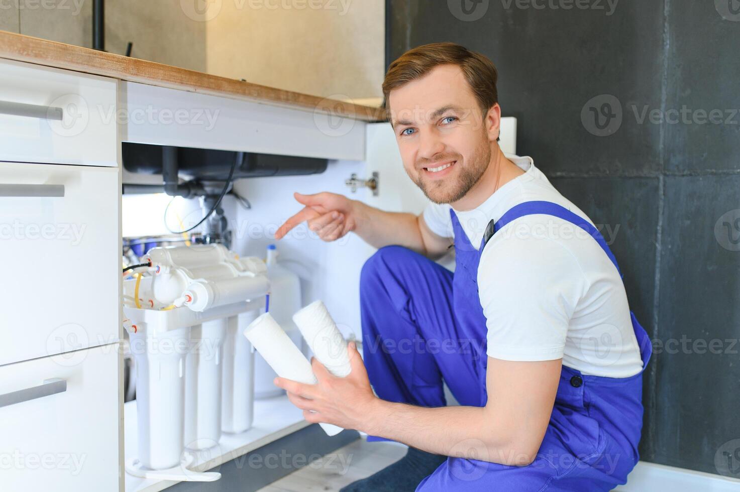 Plumber installs or change water filter. Replacement aqua filter. Repairman installing water filter cartridges in a kitchen. Installation of reverse osmosis water purification system. photo