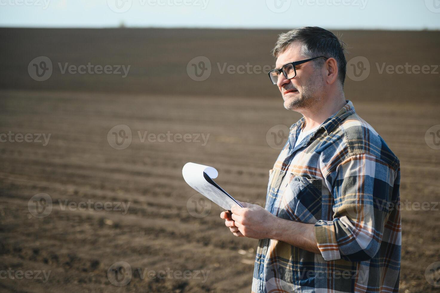 A farmer works in a field sown in spring. An agronomist walks the earth, assessing a plowed field in autumn. Agriculture. Smart farming technologies. photo
