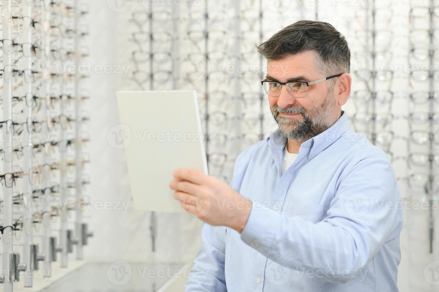 male customer choosing glasses in optics store photo