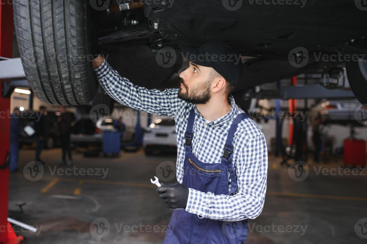 Portrait of a mechanic repairing a lifted car photo