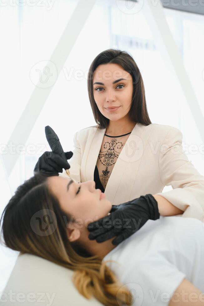 Young woman during procedure of permanent eyebrow makeup photo