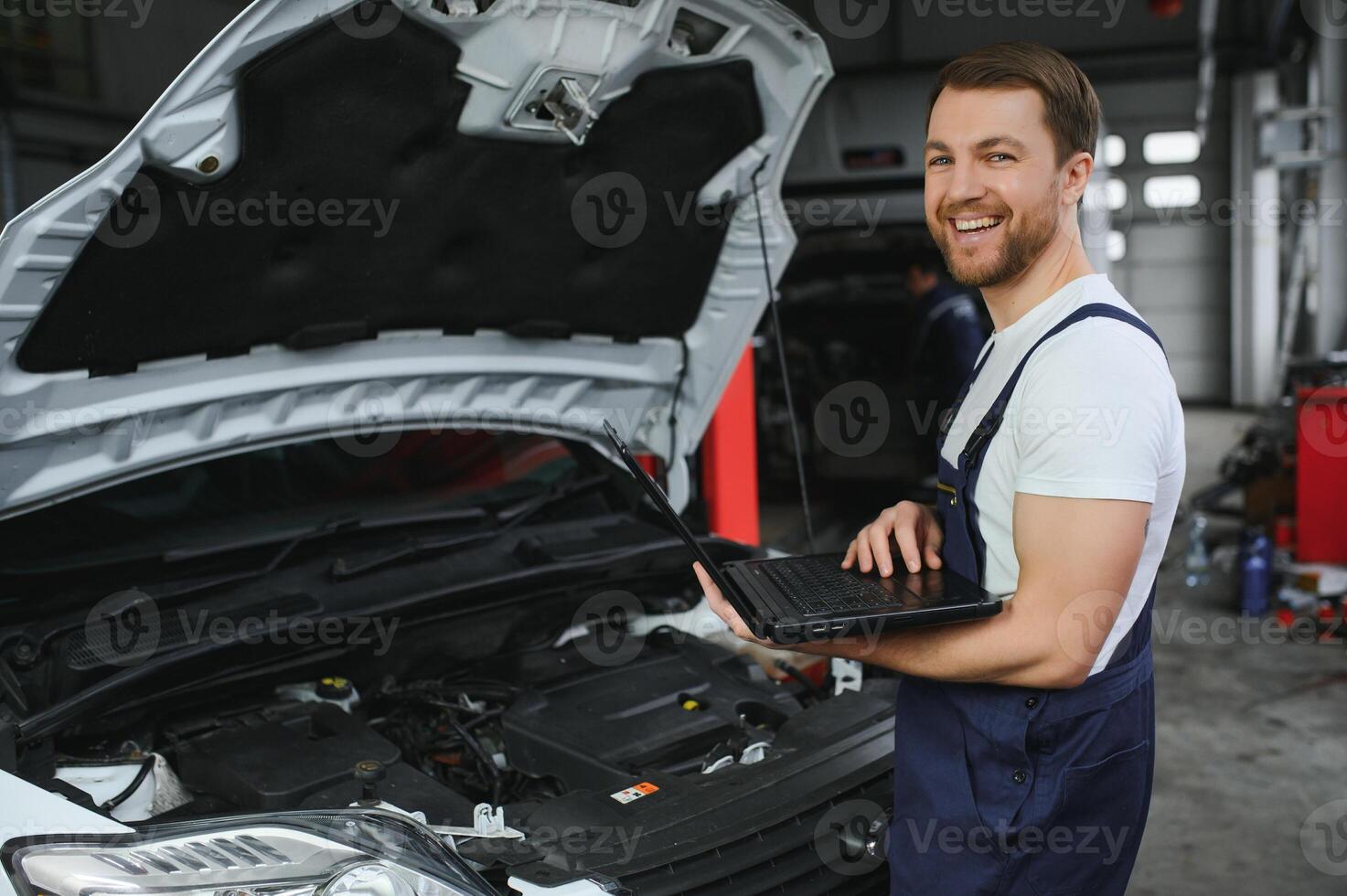 car mechanic using a computer laptop to diagnosing and checking up on car engines parts for fixing and repair photo