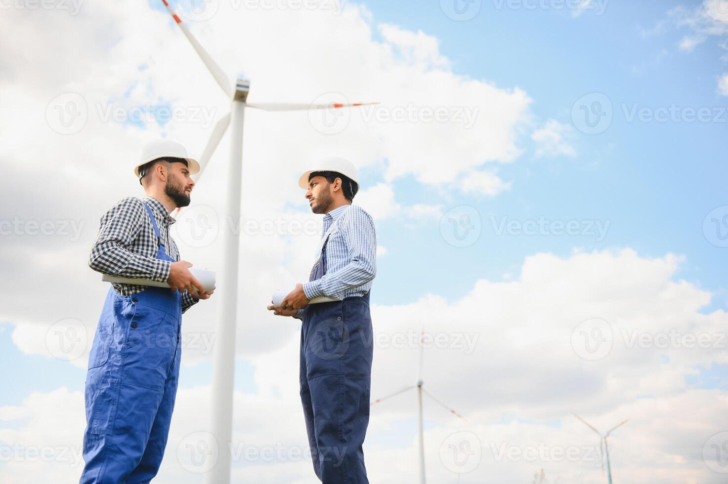 Young maintenance engineer team working in wind turbine farm. photo
