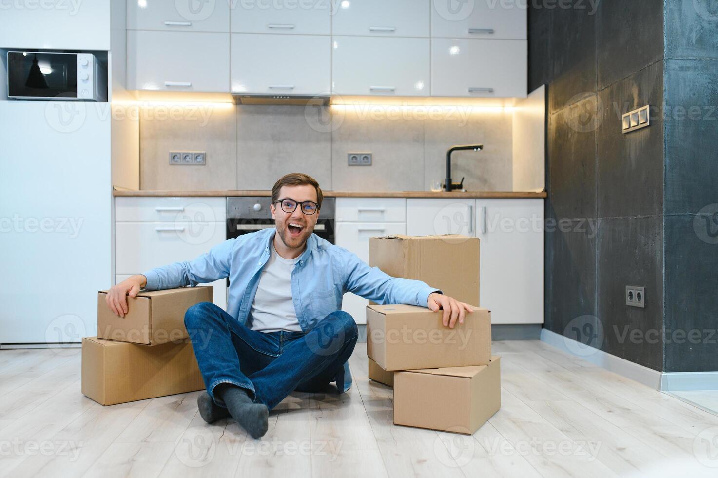 moving, people and real estate concept - happy smiling man with boxes at new home photo