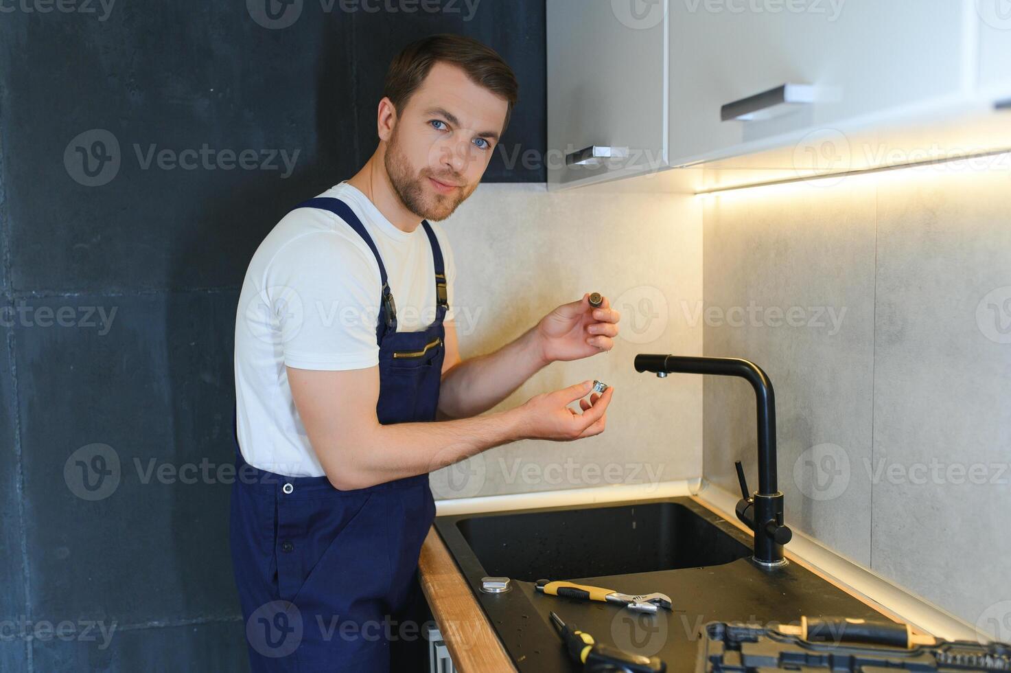 Professional plumber fixing water tap in kitchen photo
