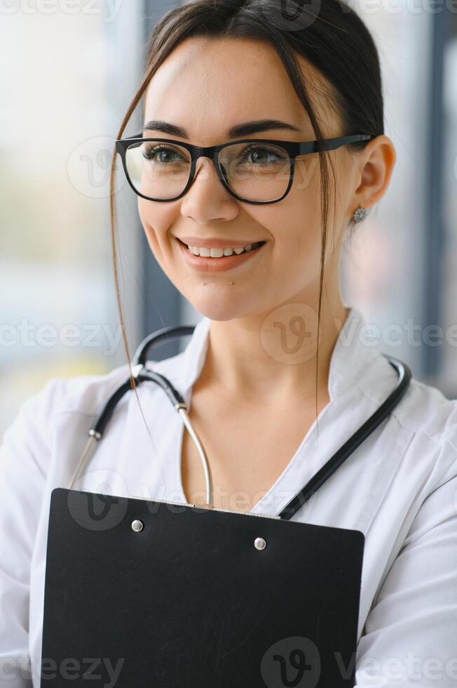 contento joven hembra médico vestir uniforme, blanco médico abrigo, estetoscopio. retrato de hermosa hembra doctor, terapeuta, enfermero. foto