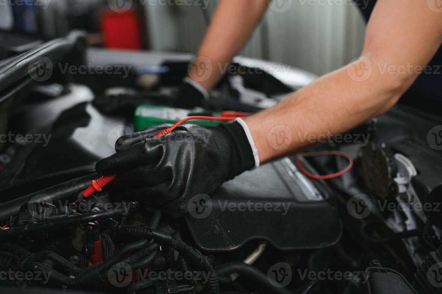 Car mechanic is using a multimeter with voltage range measurement to check the voltage level of the car battery. photo