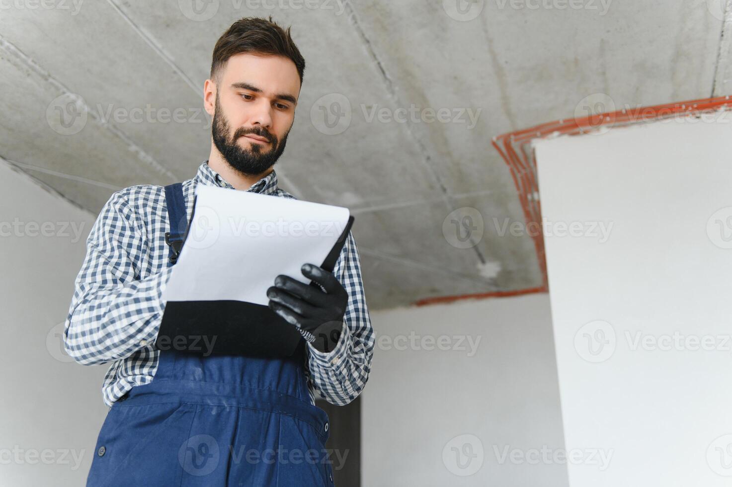 Laughing construction worker on the background of a gray concrete wall. Renovation. place for text photo