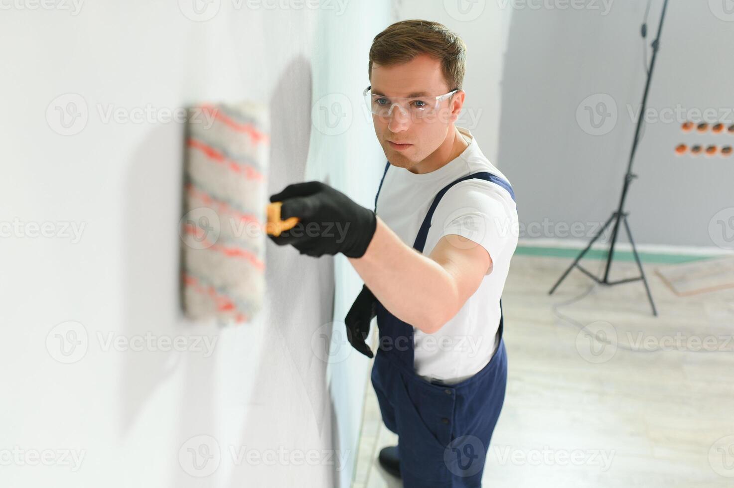 Young worker painting wall in room photo