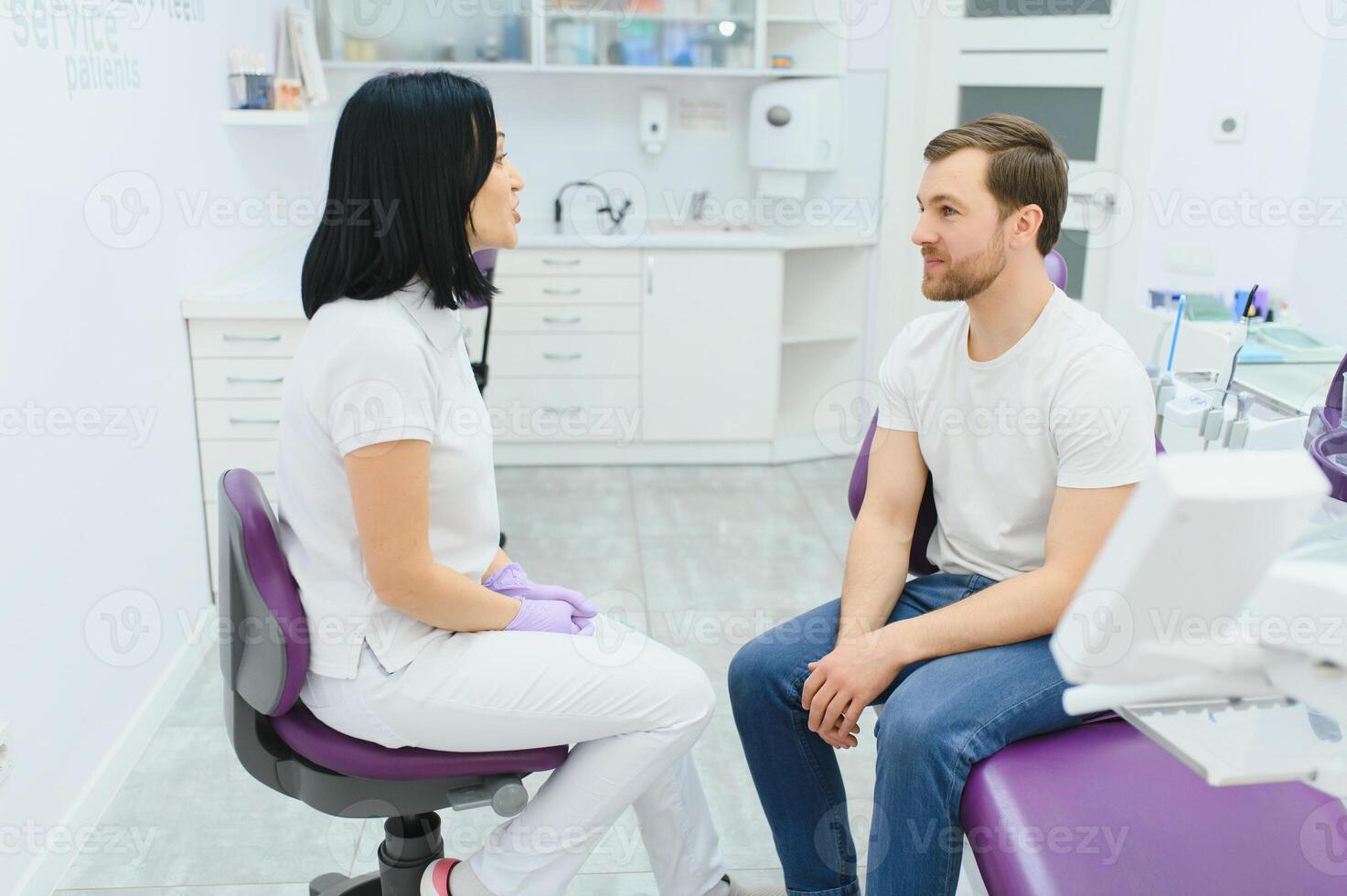 Handsome man smiling while teeth exam. Happy male patient sitting in a dentist's chair and having check up teeth. photo