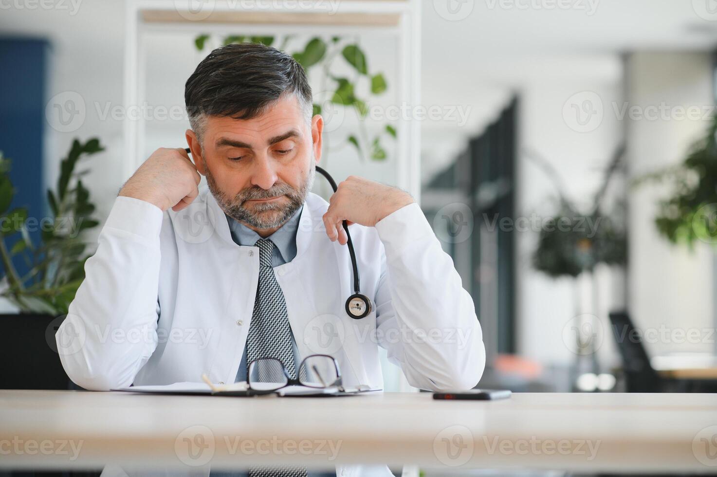 Mature doctor man at the clinic tired rubbing nose and eyes feeling fatigue and headache. stress and frustration concept. photo