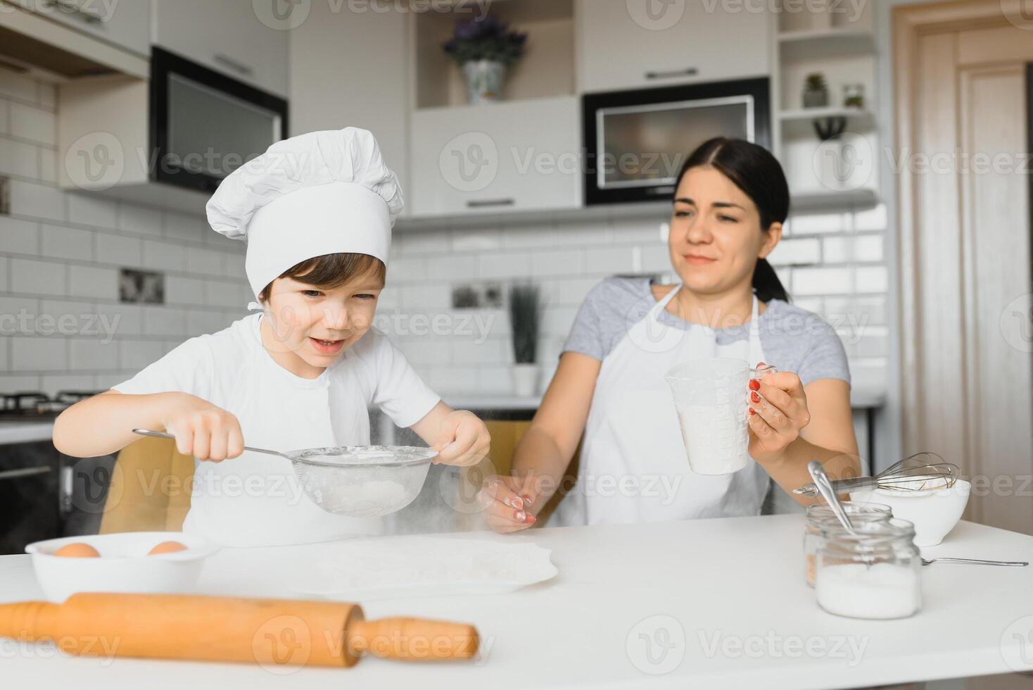 Child helping mother make cookies in modern kitchen photo