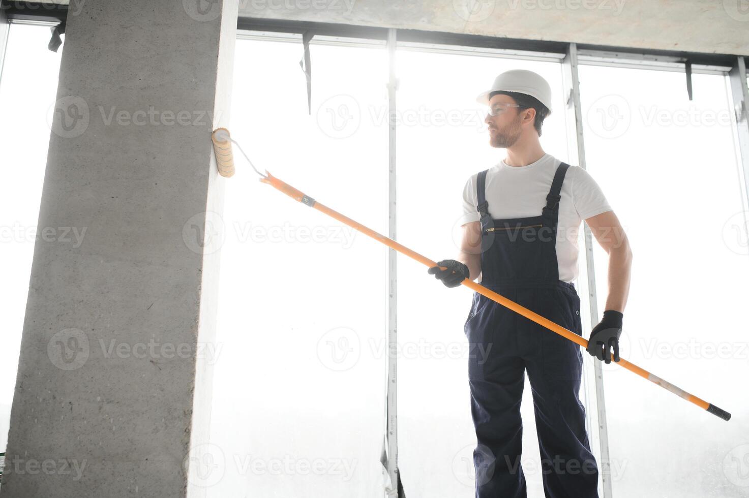 Painter man painting the wall, with paint roller. photo