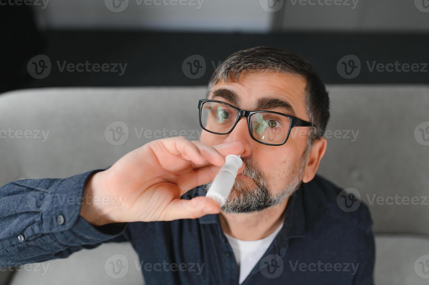 enfermo hombre con nasal rociar a hogar. foto