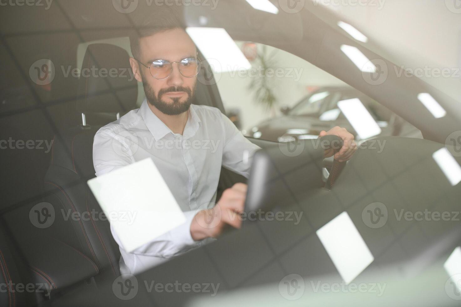 Happy caucasian man in formal wear getting inside luxury modern car for testing interior before purchase. Concept of dealership, selling and purchase photo