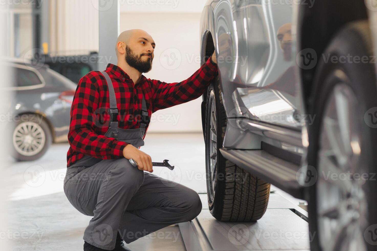 The hand of a car mechanic with a wrench in a combi zone near the car in the workshop photo