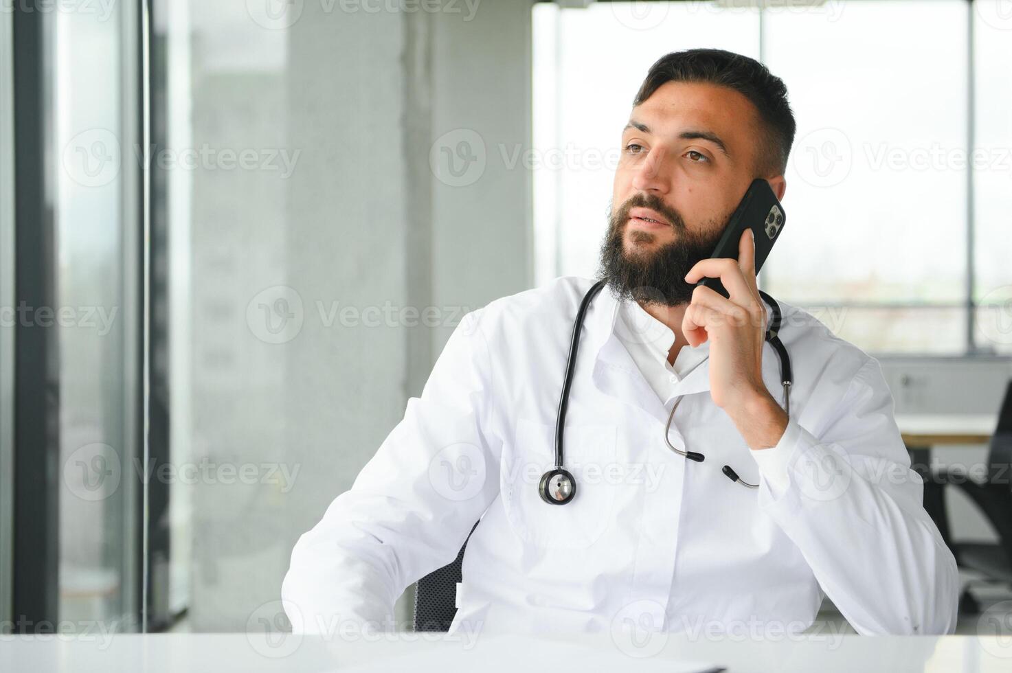 Portrait of pleasant young Arabian doctor in white coat. photo