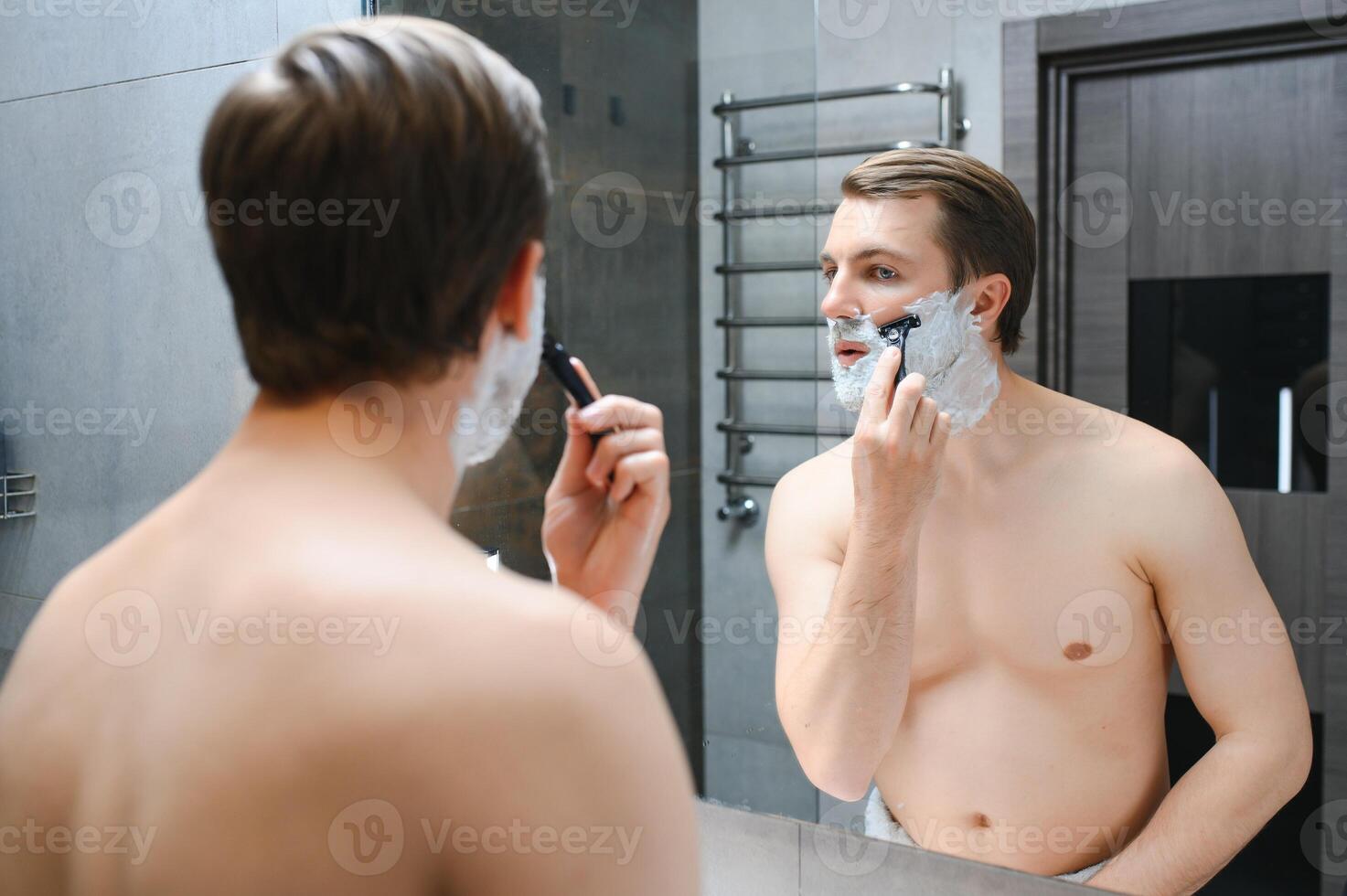 Mature handsome man shaving in front of mirror photo