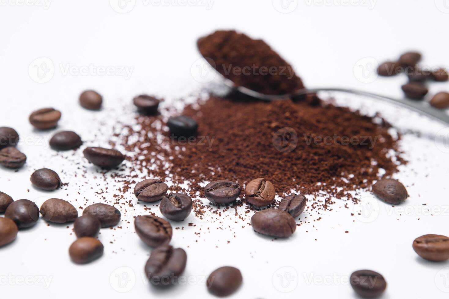 Grounded coffee in a spoon surrounded with beans isolated photo