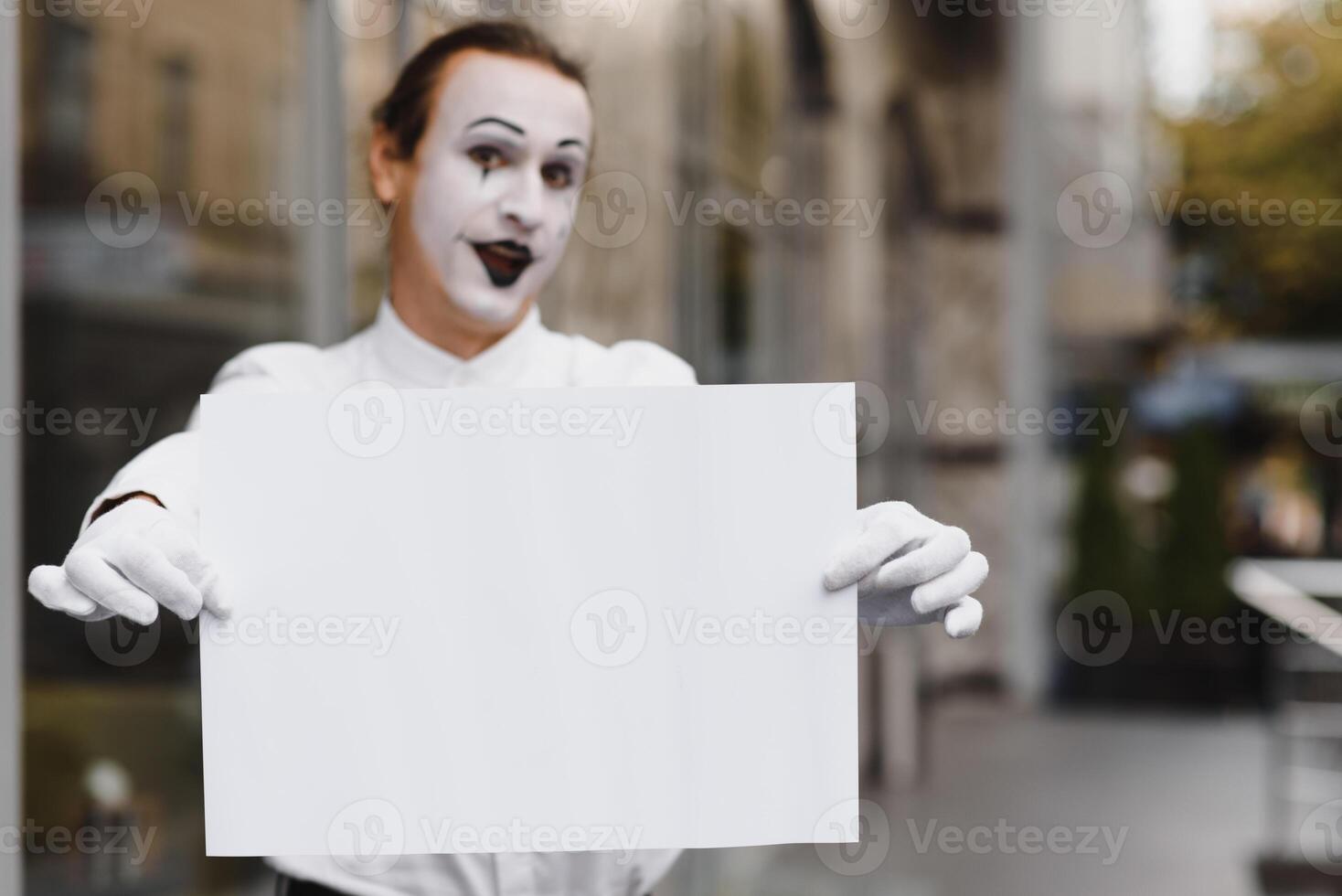 Your text here. Actor mime holding empty white letter. Colorful portrait with gray background. April fools day photo