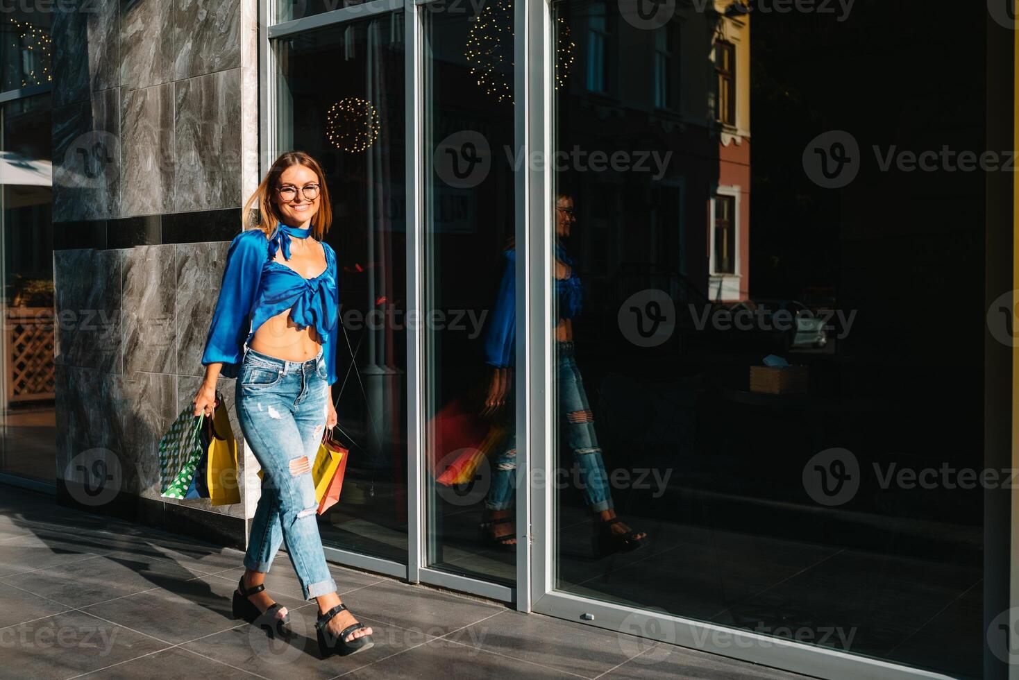 Smiling young woman posing with a handful of shopping bags. Shopping concept. photo