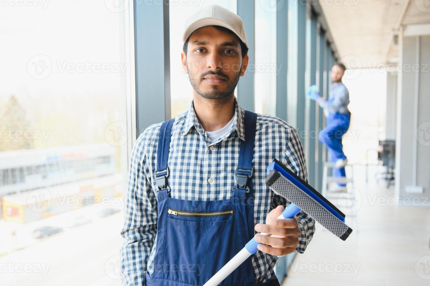 Male janitor cleaning window in office photo