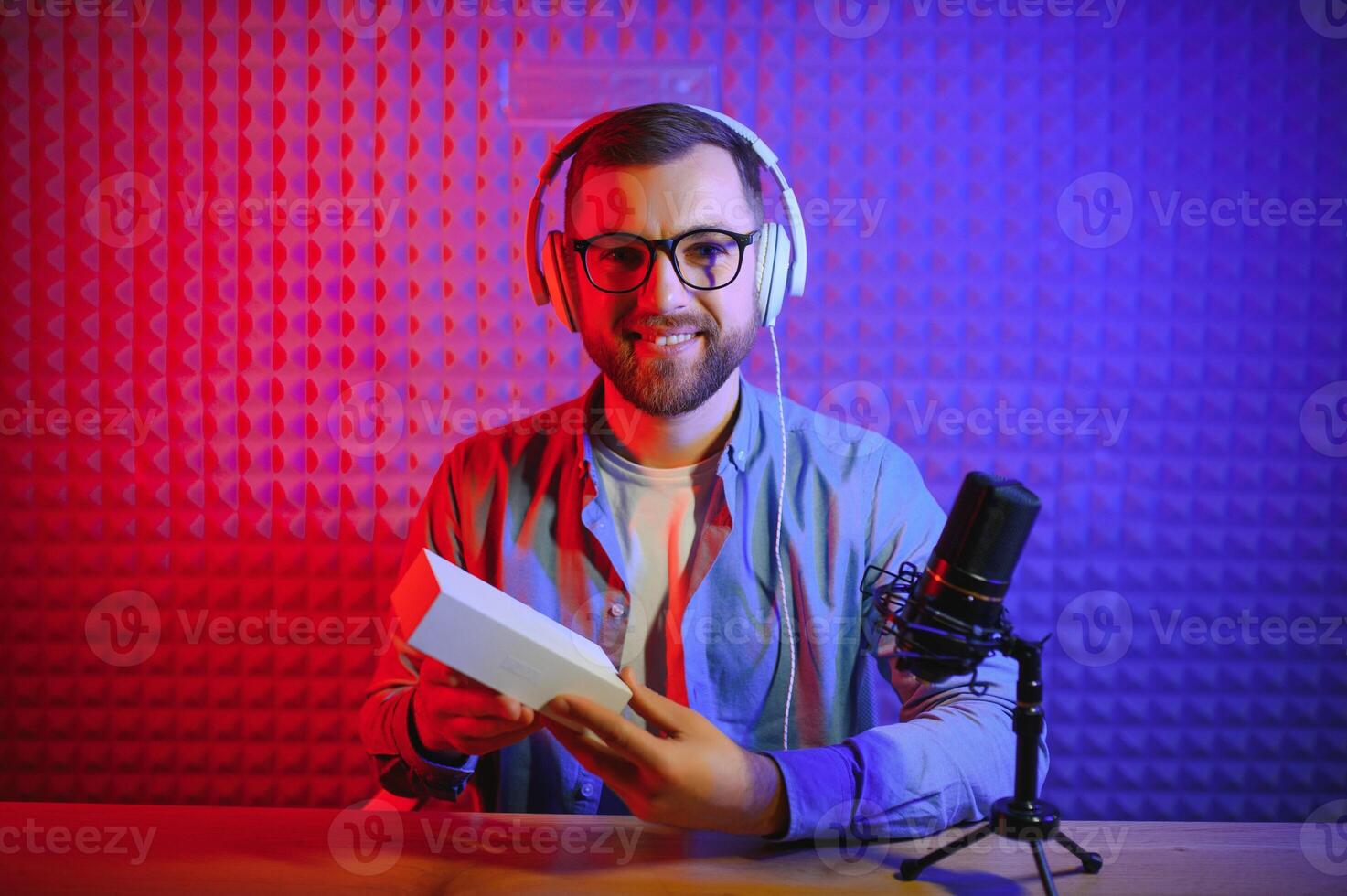 Young man recording or streaming podcast using microphone at his small broadcast studio. Content creator. photo