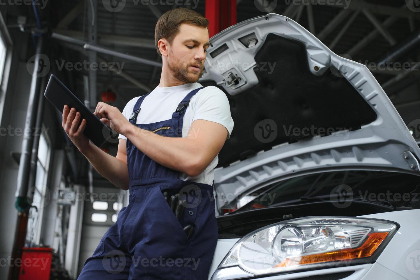 Automobile computer diagnosis. Car mechanic repairer looks for engine failure on diagnostics equipment in vehicle service workshop photo