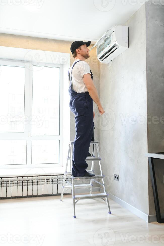 specialist cleans and repairs the wall air conditioner photo