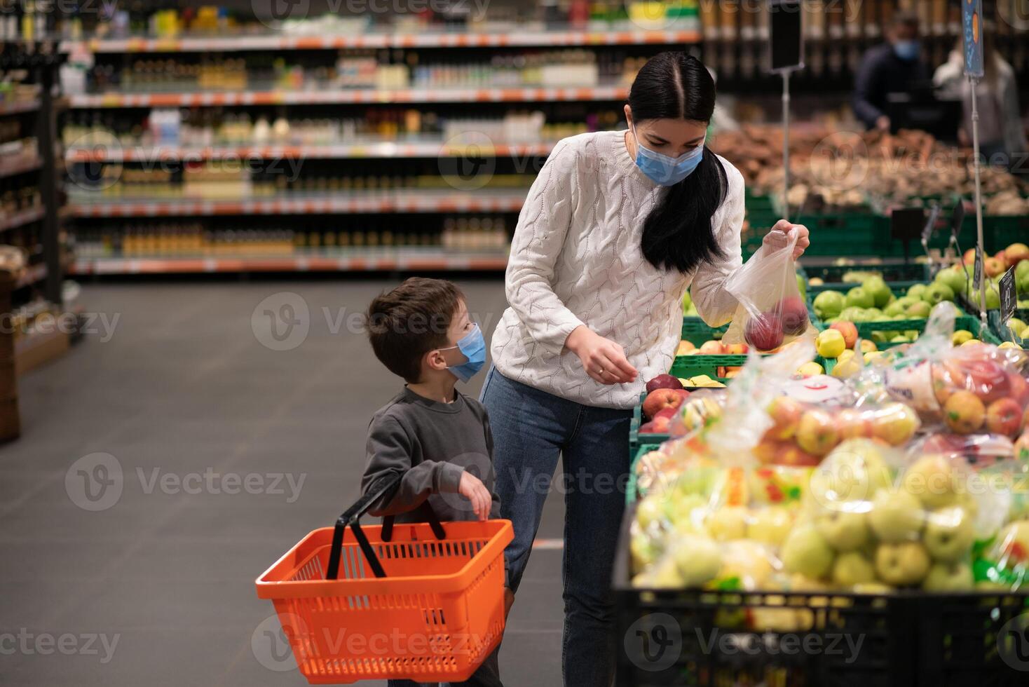 Mother and her son wearing protective face mask shop at a supermarket during the coronavirus epidemic. photo