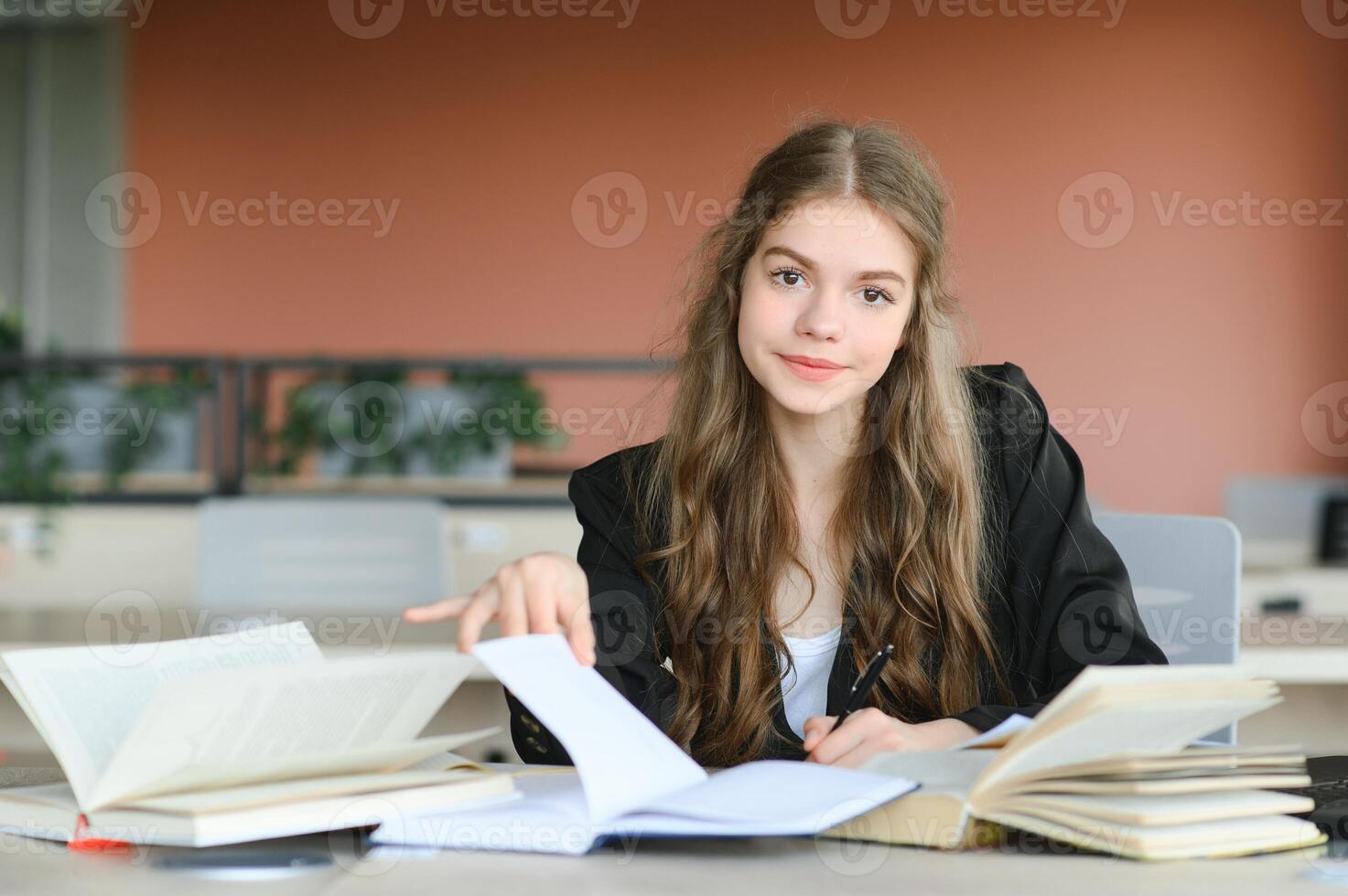Teen girl studying with textbook writing essay learning in classroom. photo