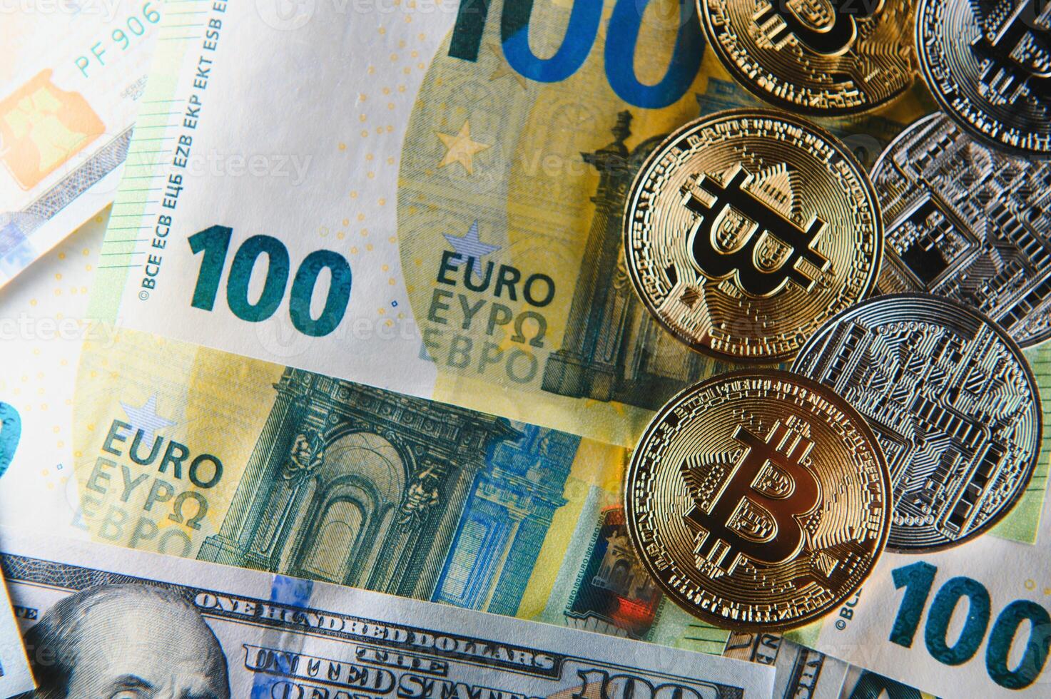 Close up heap of golden bitcoin physical coins on top of Euro, dollar banknotes background, high angle view, selective focus photo