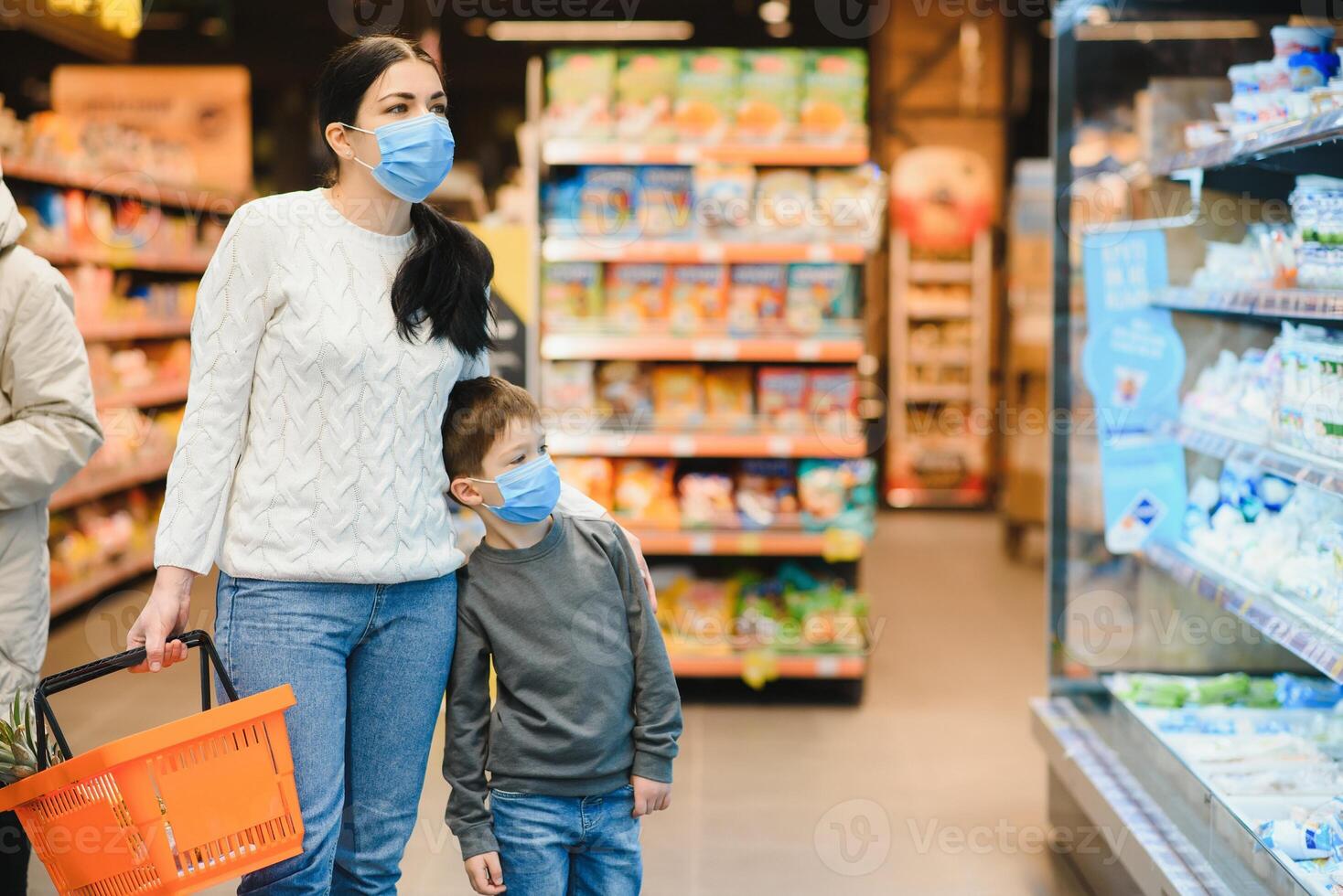 joven mujer y su pequeño hijo vistiendo protector cara máscara tienda un comida a un supermercado durante el coronavirus epidemia o gripe brote. foto