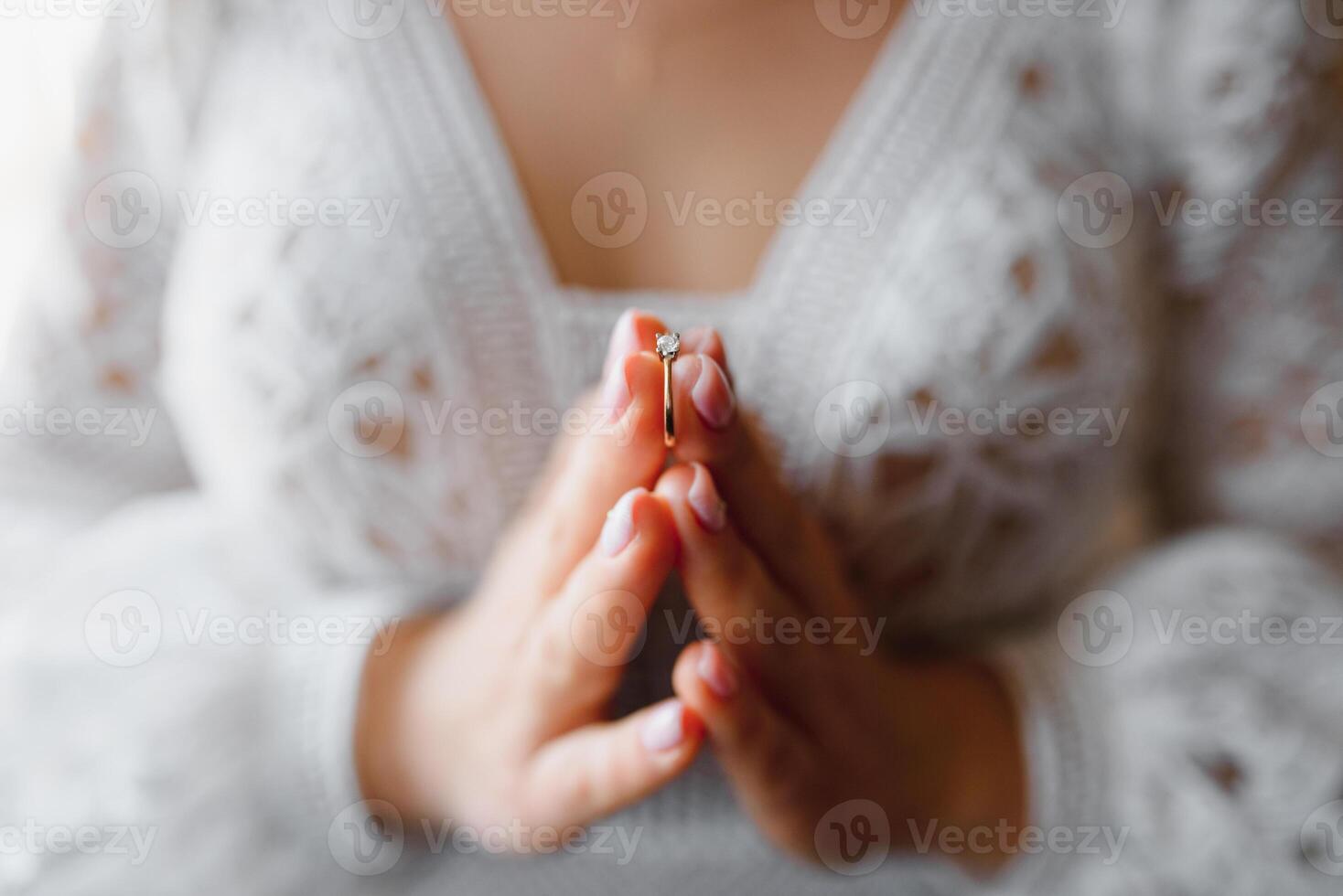 bride holds wedding ring on her hand against the background of a white lace wedding dress. body parts, hold hands. photo