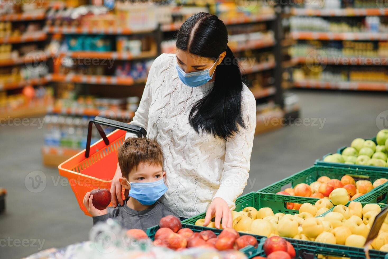 Mother and her son wearing protective face mask shop at a supermarket during the coronavirus epidemic. photo