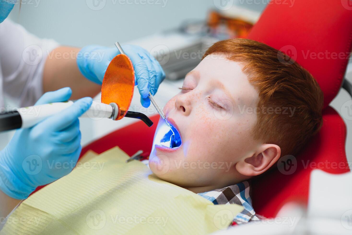 Dentist wearing mask. Red-haired child dentist wearing mask examining cute boy photo