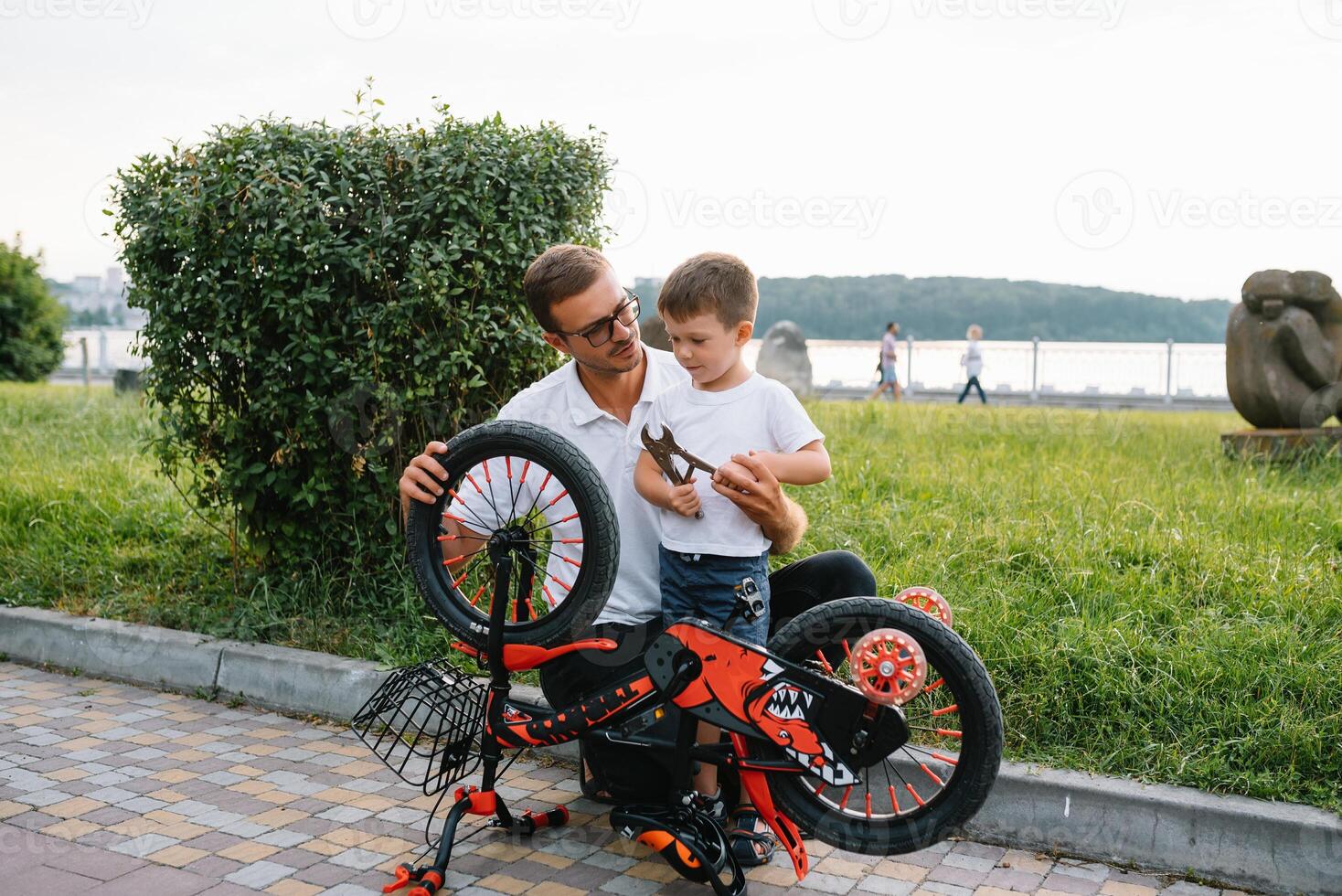 Happy father and his son having fun together at the green park, fixing bicycle together. father's day. photo