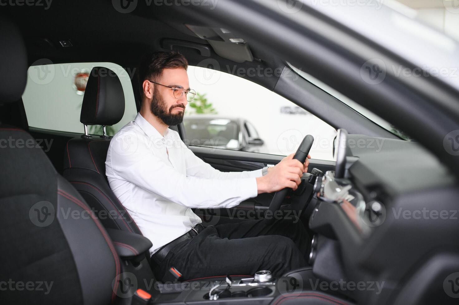 Happy caucasian man in formal wear getting inside luxury modern car for testing interior before purchase. Concept of dealership, selling and purchase photo