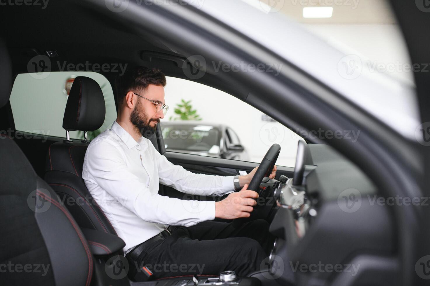 contento caucásico hombre en formal vestir consiguiendo dentro lujo moderno coche para pruebas interior antes de compra. concepto de concesión, de venta y compra foto